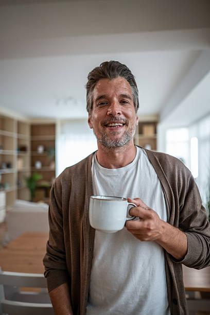 istock Smiling man holding coffee mug at home 2241147003