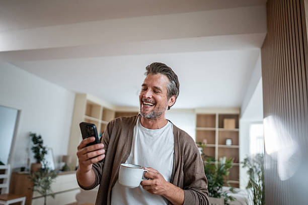istock Mature man relaxing at home, smiling, using phone 2241147058