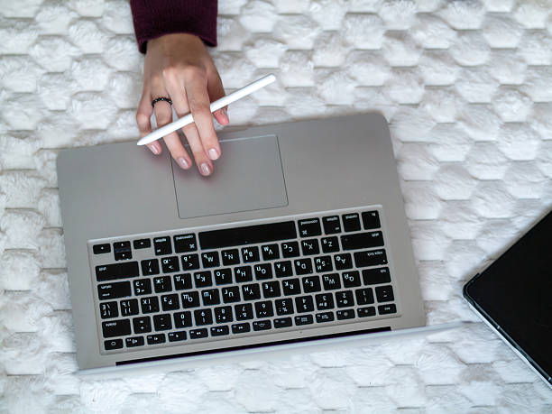 istock Engaged in working on a laptop using a stylus while comfortably seated on my bed 2241148104
