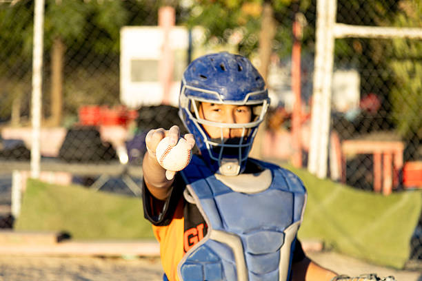 istock Young baseball catcher proudly holding ball on field 2241150188