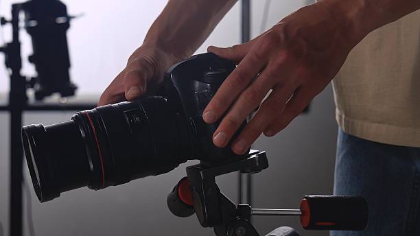 istock Photographer Adjusting Camera on Tripod Indoors 2241150547