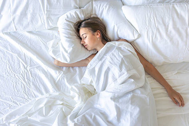 istock Girl sleeping in white sheets overhead. Calm topdown. 2241153689