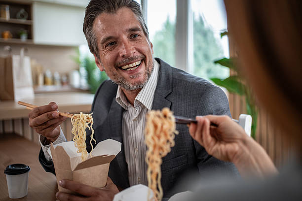 istock Business colleagues eating takeout noodles during lunch break 2241155360