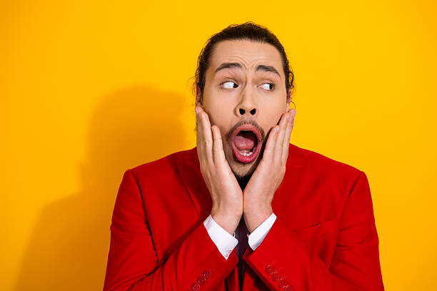 istock Man in red suit with surprised expression on bright yellow background makes a playful bold statement for fashion and entertainment 2241155423
