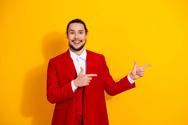 istock Funny cool gentleman in red suit points at a bright yellow background with a big smile for vibrant fashion stock photo 2241155424