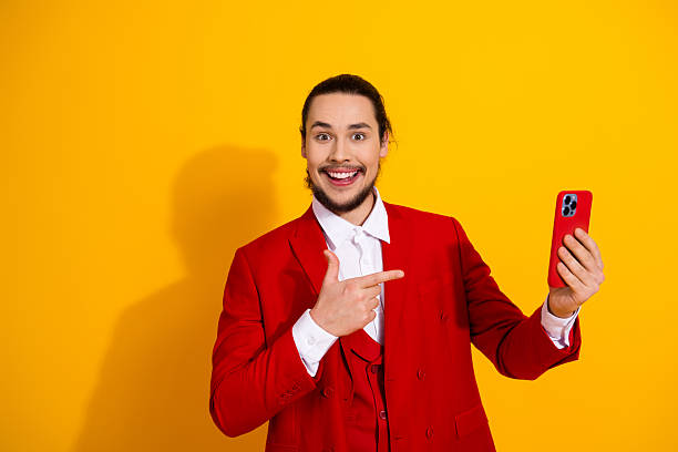 istock Whimsical red suit selfie moment by a stylish handsome model with bright yellow backdrop and funny engaging vibe for glamour fashion and holiday promotion 2241155621