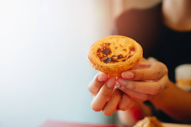 istock Egg tart concept. Freshly Baked Egg Tart Held by a Delighted Hand in a Brightly Lit Environment 2241156959
