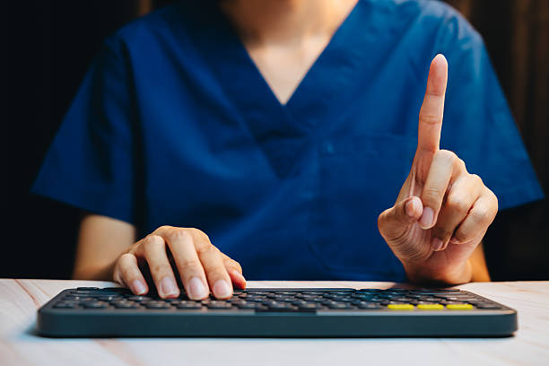 istock Healthcare Professional in Scrubs Gestures with Finger Raised While Using a Computer Keyboard in a Medical Setting 2241157636