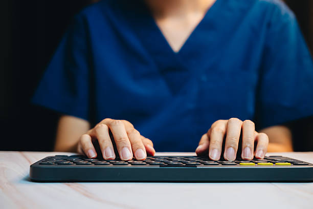 istock Medical Professional Typing on Keyboard in Blue Scrubs Focused on Digital Device while Working in a Modern Healthcare Environment 2241157754
