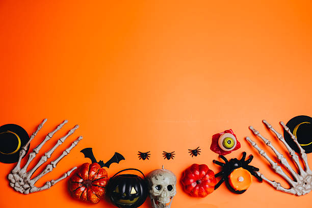 istock Halloween concept. Spooky Halloween Decor with Pumpkins, Spider, Skeleton Hands, and Skull on Vibrant Orange Background for Festive Celebration 2241159029