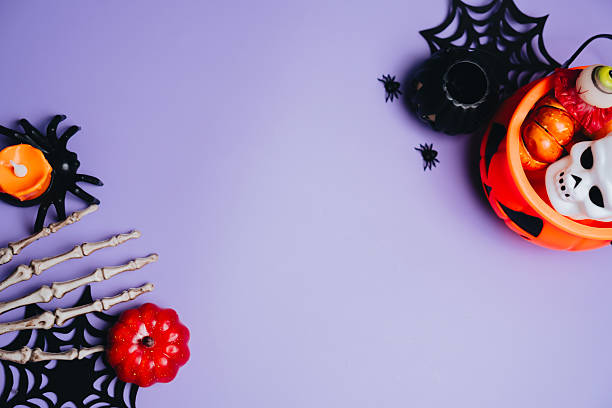 istock Halloween concept. Halloween decorations featuring pumpkins, skeleton hands, and spooky items on a purple background for festive celebration 2241159136