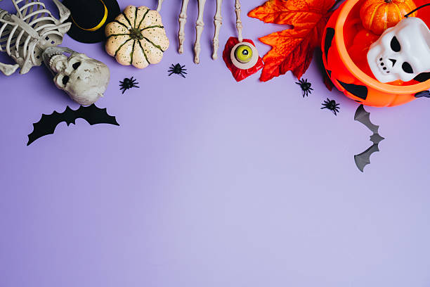 istock Halloween concept. Halloween-themed flat lay with spooky decorations, skeleton, pumpkins, bats, spiders, and festive items on purple background 2241159154