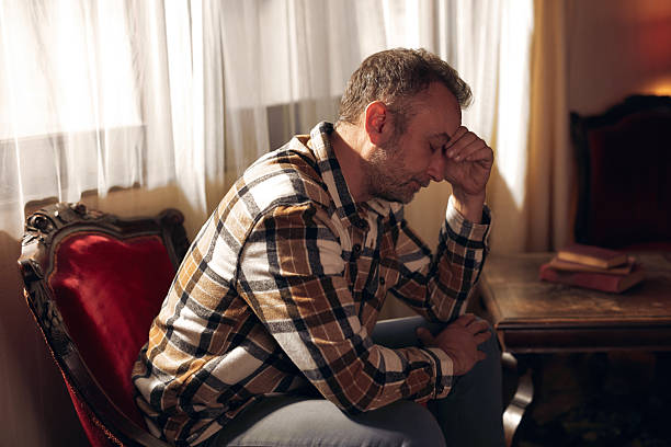 istock Man with depression and headache sitting on a chair at home. 2241160982