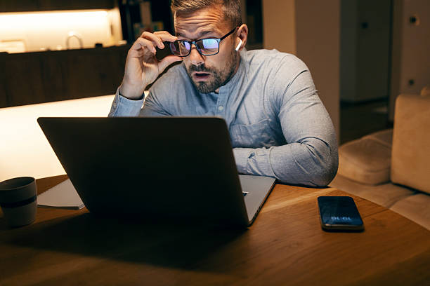 istock Man reacting with shock to content on laptop at night 2241161210