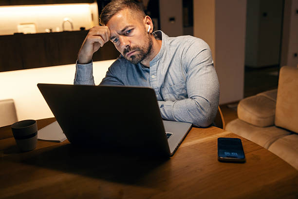 istock Stressed man working late on laptop at home 2241161217