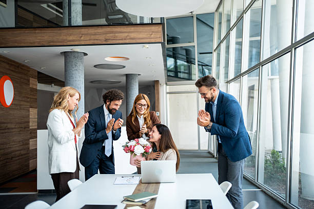 istock Business colleagues celebrating a successful project with flowers in modern office 2241165492