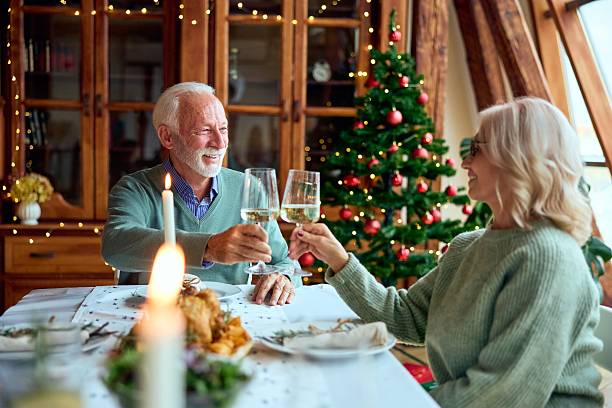 istock Warm Christmas Dinner Toast By Elderly Couple With Christmas Tree And Candlelight 2241165726