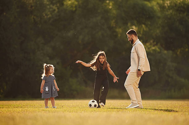 istock Man with his two daughters, playing on the field with soccer ball 2241170432