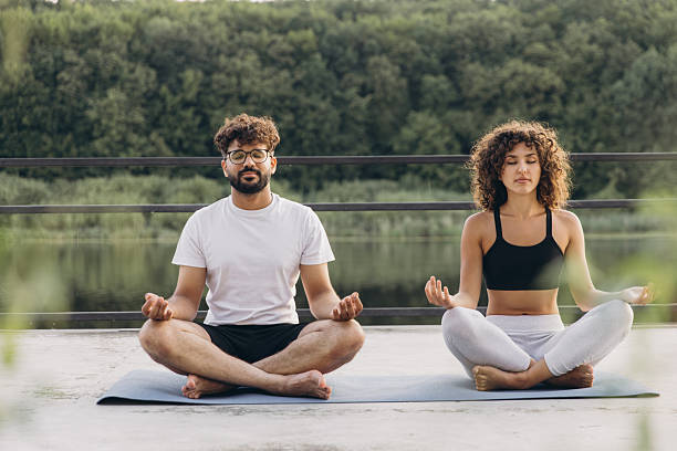 istock Couple Meditating Outdoors by the Lake, Finding Serenity Together 2241172029