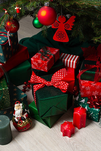 istock Traditional green and red gift boxes nestled beneath the Christmas tree, surrounded by glowing candles and festive decorations, creating a cozy and joyful holiday setting 2241173546