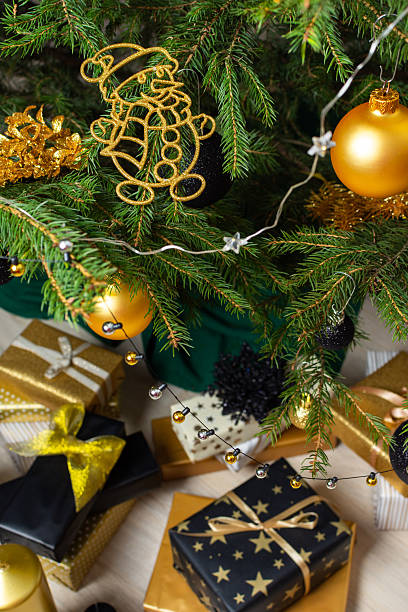 istock A festive scene featuring gold and black gift boxes, surrounded by shimmering candlelight and stylish decorations under a beautifully decorated Christmas tree, exuding elegance and charm 2241173557