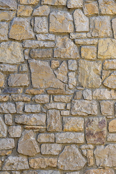 Wall made of stone with a rough texture. The wall is brown and has a stone-like appearance