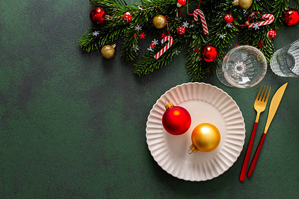 istock A beautifully set Christmas table with an empty plate, cutlery on a deep green background. Red tree ornaments and spruse branches complete the festive charm 2241175064