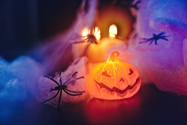 istock Halloween jack-o'-lantern and spider in webs with candle glow 2241175662