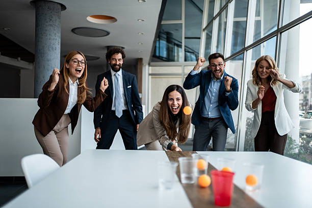 istock Business people playing beer pong in modern office 2241177012