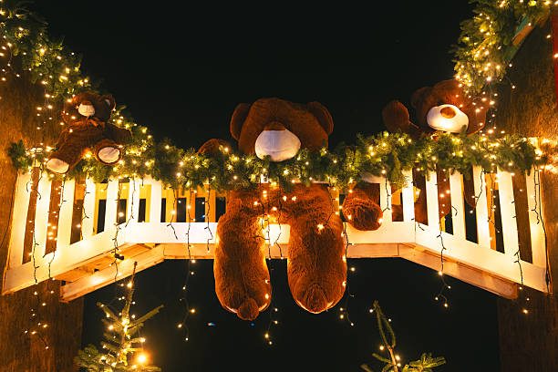 Three plush bears on festive garland with fir trees and string lights at night