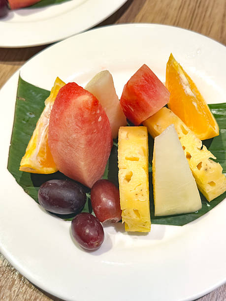 istock Assorted Fresh Fruits on Banana Leaf with Juice in Dining Setting 2241183652