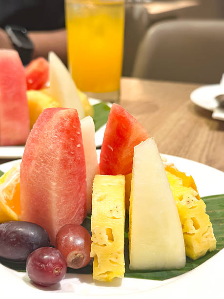 istock Assorted Fresh Fruits on Banana Leaf with Juice in Dining Setting 2241183781
