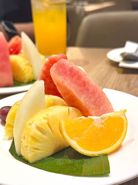 istock Assorted Fresh Fruits on Banana Leaf with Juice in Dining Setting 2241183917