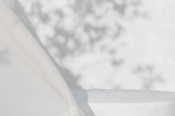 istock White concrete empty table, organic curtain and plant shadow on cement wall. Summer exterior scene for product placement mockup. Neutral minimal aesthetic. 2241185505