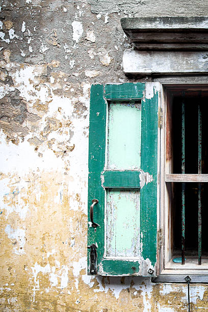 istock Vertical vintage green window on an old, textured wall. Features Art Deco elements and peeling paint, showing age and decay. 2241186694