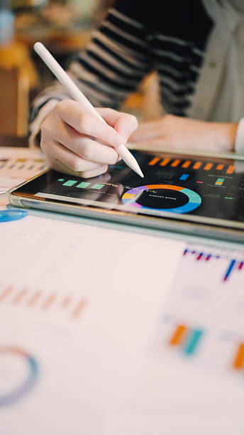 Professional using tablet with financial charts while reviewing printed corporate statement. Highlights digital transformation in finance, investment decision making, and data-driven business strategies for the global economy.