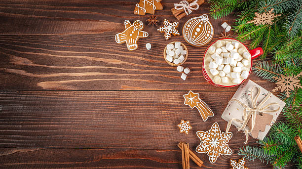 istock Festive Christmas composition with hot cocoa and marshmallows, gingerbread cookies, gift box, and fir branches on a rustic wooden background. copy space. top view 2241190353