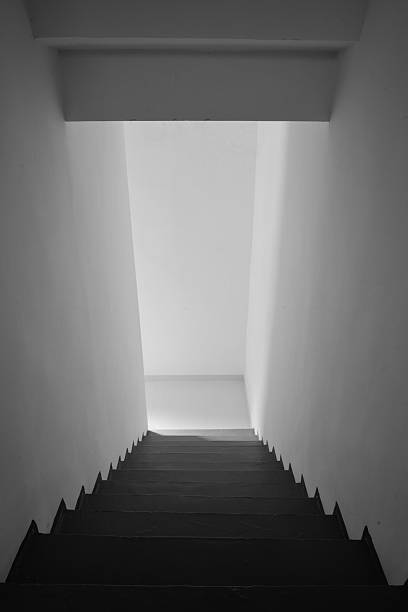 istock Dramatic Black and White Staircase Ascending to Ethereal Light in Minimalist Corridor 2241191079
