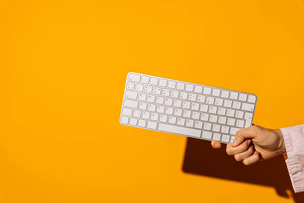 istock Hand holding wireless keyboard on bright orange background 2241191934