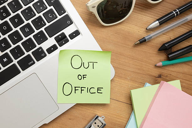 Green Sticky Note with Out of Office Message on Desk