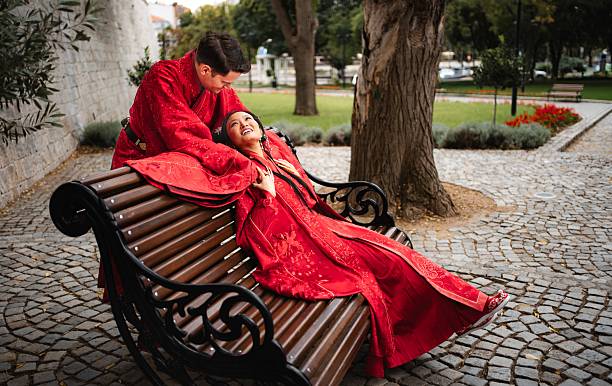 Happy couple wearing red qipao bridal outfits, looking at each other warmly