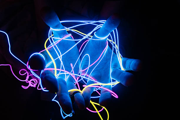 istock Man's Open Hands Tangled in Neon Wires Glowing in the Dark 2241199623