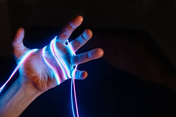 This is an abstract photo of a man’s hands illuminated with neon electric wires.