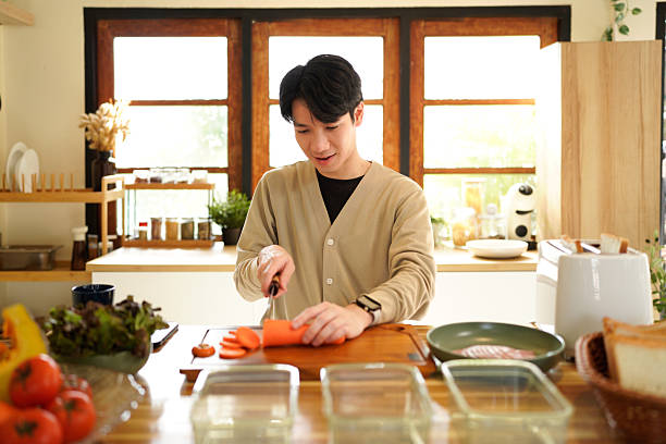 istock A man is cutting a carrot on a wooden cutting board. 2241202324