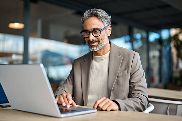 istock Smiling mature business man entrepreneur using laptop working outside office. 2241204431