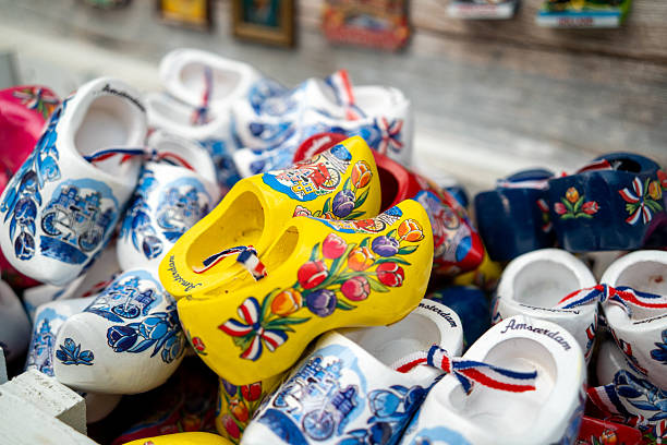 Old wooden Dutch shoes - klomps. A lot of colorful old clomps against the background of a wooden wall. Popular souvenirs. Traditions of Holland. Background
