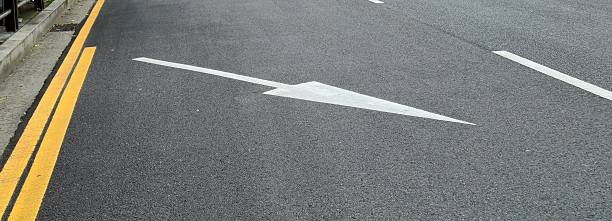 istock White directional arrow painted on a black asphalt road 2241207436