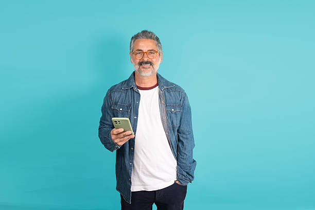 istock Man smiling holding smartphone in hand 2241208099
