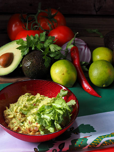 istock Guacamole in a red bowl, with ingredients at the back 2241209619