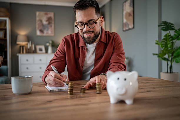 istock Man managing finances saving money at home 2241209750
